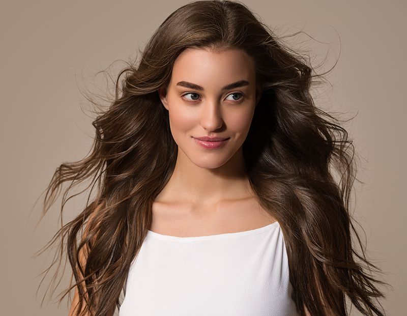 Beautiful happy woman with long hair in white dress over color b